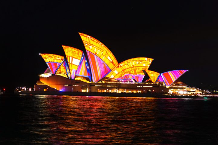 a boat that is lit up at night with Sydney Opera House in the background